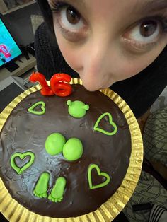 a woman is holding a cake with chocolate frosting and green decorations on the top