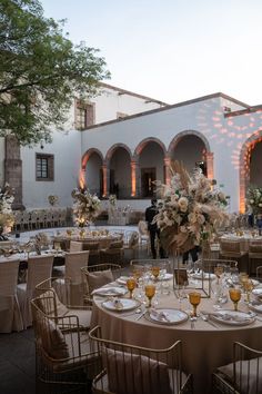 tables and chairs are set up in front of an outdoor venue with white flowers on them