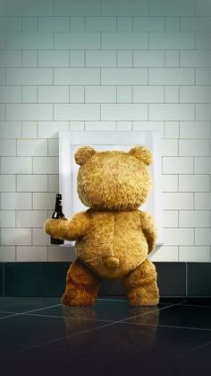 a large teddy bear standing next to a urinal in a tiled room with white walls