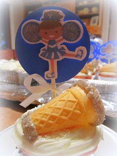 an ice cream sundae with a doll on top is sitting on a plate in front of other desserts