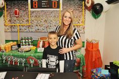 a woman standing next to a young boy in front of a table with football decorations