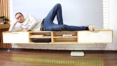 a man laying on top of a tv stand