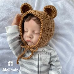 a baby wearing a bear hat laying on top of a bed