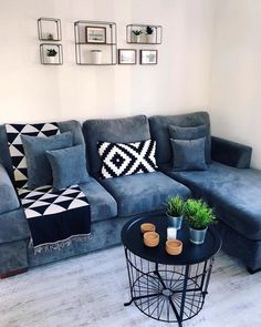 a living room with a blue couch and black table in front of the couch is decorated with pictures on the wall