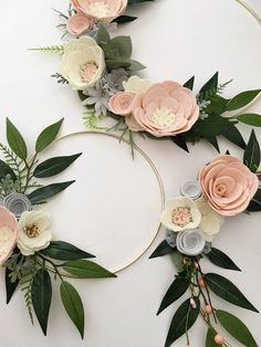 a white table topped with pink flowers and greenery next to a hoop filled with green leaves