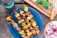 skewers of meat and vegetables on a blue plate next to a cutting board