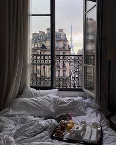 an unmade bed in front of a window overlooking the eiffel tower