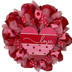 a red and pink heart shaped wreath with the word love on it's center