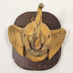 an elephant head on top of a wooden plaque