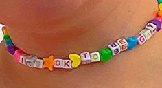 a close up of a person wearing a necklace with letters and stars on it's side