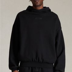 The Fear Of God Essentials Jet Black Hoodie Features An Oversized Fit, A Mock Neckline, Long Sleeves, Side Seam Pockets, An Attached Hood, Contrast Stretch Binding, And Rubber Brand Labels At The Center Front And Upper Back. Solid Color Hoodie Attached Hood Long Sleeves Mock Neckline Dropped Shoulders Side Hand Pockets Front & Back Rubber Brand Labels Contrast Stretch Binding Relaxed Fit 80% Cotton, 20% Polyester Brushed Back Fleece Hand Wash, Flat Or Line Dry Black Techwear Tops With Ribbed Cuffs, Black Sweatshirt With Double-lined Hood And Relaxed Fit, Black Sweatshirt With Double-lined Hood In Relaxed Fit, Black Relaxed Fit Sweatshirt With Double-lined Hood, Black Hoodie With Double-lined Hood And Relaxed Fit, Urban Hoodie With Funnel Neck And Ribbed Cuffs, Black Relaxed Fit Hoodie With Drawstring Hood, Oversized Hoodie With Ribbed Cuffs And Funnel Neck, Oversized Black Hoodie With Ribbed Cuffs