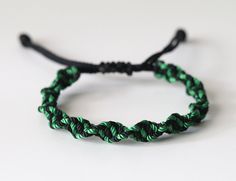 a green and black rope bracelet sitting on top of a white table