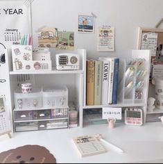 a desk with books, toys and other items on it in front of a wall calendar