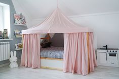 a bedroom with a pink canopy bed in the corner and a stuffed animal on the floor