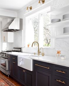 a kitchen with black cabinets, white counter tops and gold pulls on the faucets