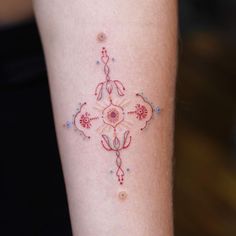 a woman's arm with a cross tattoo on the left side of her leg