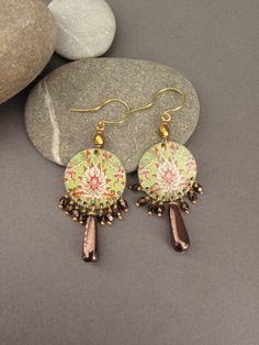 "I made these earrings from a brass plate that I cut and then decorated with an image representing a Chinese ornamental pattern. I attached a matte golden brown faceted bead at the top and and at the bottom of the loop, using gold colored brass headpins, small faceted Czech beads and a longer drop bead with flat sides of chocolate color. The pattern is covered with several layers of matt varnish to protect it. The earrings are mounted on handmade pure brass earhooks. Length (with hook)  6 cm  - Elegant Czech Glass Earrings With French Hook, Elegant Green Czech Glass Earrings, Chinese Floral Pattern, Gold Czech Glass Jewelry, Hand-strung, Artisan Green Czech Glass Earrings, Gold Flower-shaped Earrings With Czech Glass, Ornamental Pattern, Brass Plate, Chocolate Color