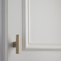 an open door with a brass handle on it's left side and a white wall in the background