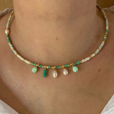 a woman wearing a necklace with pearls and turquoise beads on it's neck,