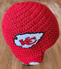 a red knitted hat with the kansas chiefs logo on it sitting on a wooden surface