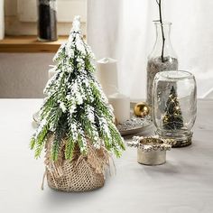 a small christmas tree sitting on top of a table next to other holiday decorations and candles