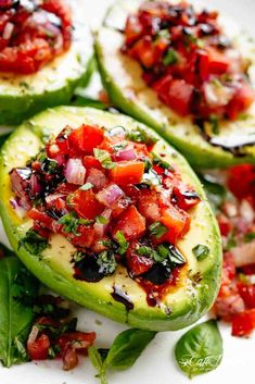 stuffed avocados with salsa and spinach leaves on a white plate, ready to be eaten