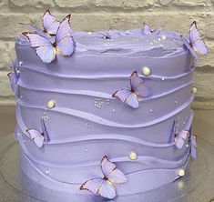 there is a purple cake with butterflies on the frosting and icing, along with pearls