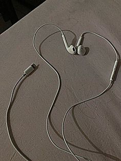 an earbud laying on top of a bed next to a pair of headphones