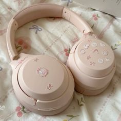 a pair of pink headphones laying on top of a floral print bed sheet next to a box