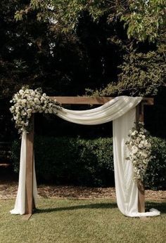 an outdoor wedding setup with white flowers and draping