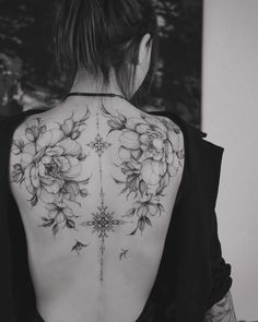 a woman's back tattoo with flowers on it