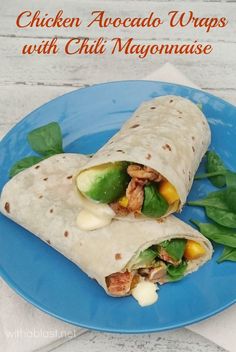 chicken avocado wraps with chili mayonnaise on a blue plate next to spinach leaves