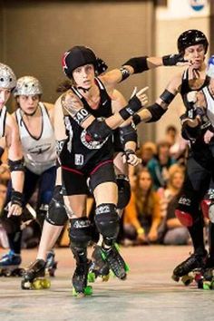 several people on roller skates in front of an audience at a roller derby event