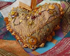 a heart - shaped pillow with buttons and chains on it sits on a quilted surface