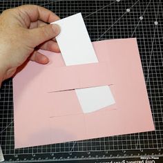 someone is cutting out some paper to make an origami house with the letter e on it