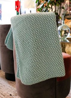 a green blanket sitting on top of a brown chair