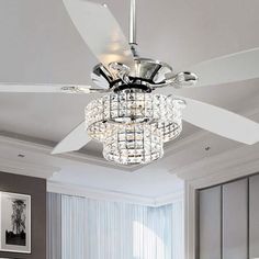 a white ceiling fan with crystal chandelier hanging from it's blades in a living room