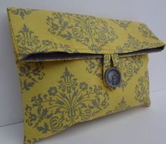 a yellow and gray bag with a button on it's side, sitting against a white wall