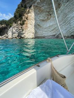 there is a boat that is in the water near some rocks and cliffs on the shore