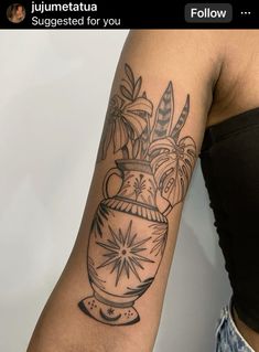 a woman with a tattoo on her arm has a vase full of flowers in it