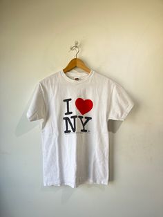 Vintage I Heart NY Tee. Fruit of The Loom - heavy weight 100% cotton. Logo on front. Lightly worn, small discoloration near logo. Size M, machine wash regular. Approximate measurements:Underarm to underarm: 17"Length: 25" I Heart Ny, I ❤ Ny, Cotton Logo, The Loom, Fruit Of The Loom, Heavy Weight, Loom, Shirts Tops, Fruit