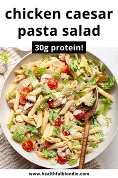 chicken caesar pasta salad with tomatoes and lettuce in a white bowl on a table