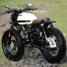 a white motorcycle parked on top of a rocky field