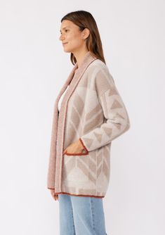 An ultra warm and cozy mid-length sweater with a contrast trim. Abstract geometric pattern Fuzzy texture Relaxed fit Contrasting trim Long sleeve Drop shoulder Shawl collar Mid-length Open front Side patch pockets Bohemian cardigan Wrap yourself in comfort this Fall with our soft fuzzy knit cardigan. This effortlessly cool and casual mid-length piece features essential side pockets, an open front, and long sleeves with a relaxed dropped shoulder. Its cozy, fuzzy texture is so comforting, you mig Bohemian Cardigan, Soft Texture V-neck Cardigan For Loungewear, Abstract Sweater, Cozy One Size V-neck Cardigan, Cozy Cotton V-neck Cardigan, Cozy V-neck Merino Wool Cardigan, Shoulder Shawl, Cozy V-neck Cardigan With Pockets, Fuzzy Texture