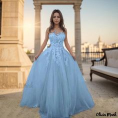 a woman wearing a blue dress standing in front of a building with columns and pillars