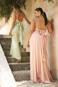 two women in dresses standing on steps with their back to the camera, one wearing a pink dress