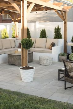 an outdoor living area with couches, tables and potted plants on the patio