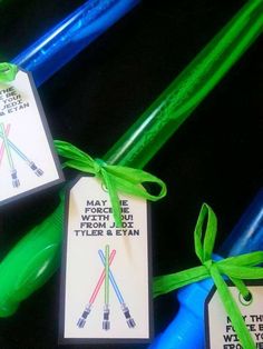 two tags with green ribbons tied to them on blue and green plastic straws in the shape of toothbrushes