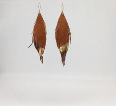 A beautiful fun pair of earrings, these are made using the finest quality soft natural tan leather with gold leaf tips. They are so light and soft, you will barely know that you are even wearing earrings. The color is the perfect accent to any outfit and is incredibly versatile. The gold simply pops from the brown background that gives a stunning iridescence when they swivel! They measure approximately 4 inches in length. The earring hooks are gold plated. If you would like a different size, ple Elegant Brown Feather Earrings, Brown Feather Dangle Earrings, Adjustable Gold Feather Earrings, Leather Feather Earrings, Brown Background, Natural Tan, Soft Natural, Earring Hooks, Etsy Earrings Dangle