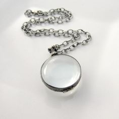 "A gorgeous locket, with an heirloom feel, is the focal of this choker style necklace. The round locket is made of translucent pale green glass encased in sterling silver. The bail swivels so the contents can be seen from both side. The locket is lovely all by itself, but does open at the top so that you can place your treasures inside. A piece of lace, a feather, or your favorite photos will be kept secure with a screw closure. The pendant sways from a chunky silver link chain. The textured ste Elegant Handmade Metal Locket Necklace, White Round Locket Necklace, White Locket Necklace For Memorial, Classic White Locket Necklace, Vintage Charm Locket Necklace, Victorian Silver Jewelry With Adjustable Chain, Vintage Necklaces With Adjustable Chain For Keepsake, Vintage Keepsake Necklace With Adjustable Chain, Victorian Keepsake Necklaces